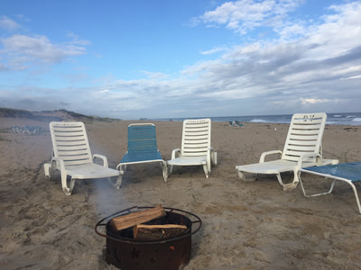 the bonfire and lounge chairs on the beach in the hamptons